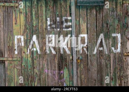 Alte strukturierte, schäbige, schicke Holztür ohne Parkplätze in kroatischer Sprache, kein Parkplatz, abblätternde Farbe an Holztüren Stockfoto