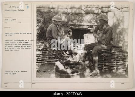 Amerikanische Infanteristen in Italien bereiten Handgranaten in einem Graben in der Piave vor. Sie schmeißen die Zünder nieder, bevor sie sie in die österreichischen Leitungen schleudern. Dieses Bild wurde am 4. November 1918 von einem Fotografen des Signal Corps aufgenommen. Es wurde am 8. November 1918 vom A.E.F.-Zensor genehmigt. Stockfoto