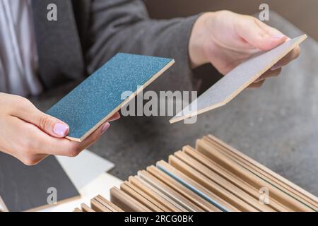 Beispiele für die Auswahl des Geschlechts. Eine Frau wählt farbige Holzstücke aus, um ein Geschlecht auszuwählen. Das Konzept der Reparatur oder Verlegung eines neuen Bodenbelags. Stockfoto