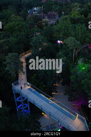 Beelitz, Deutschland. 14. Juli 2023. Die Wege auf dem Gelände des „Baum & Zeit“-Baumwipfels in Beelitz-Heilstätten sind farbenfroh beleuchtet. An drei Abenden im Juli und August bietet der Abenteuerbereich seinen Gästen ein Abendprogramm mit Musik, Lichtinstallationen und Vorstellungen. Kredit: Monika Skolimowska/dpa/ZB/dpa/Alamy Live News Stockfoto