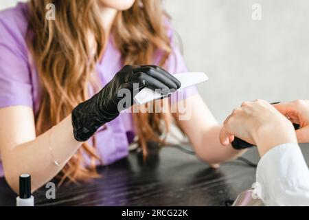 Professioneller Meister der Maniküre im Schönheitssalon. Maniküre, Handbehandlungen, Verfahren für Nägel, Finger. Mehrfarbiger Nagellack, Proben Stockfoto