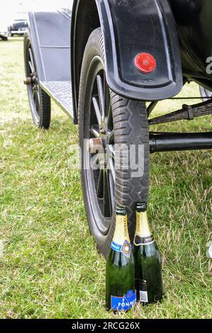 Leere Champagnerflaschen, die von einem Picknick auf dem Parkplatz des Goodwood Revival Retro-Motorsport-Events übrig geblieben sind. Historisches Auto auf Gras. Pommery Stockfoto