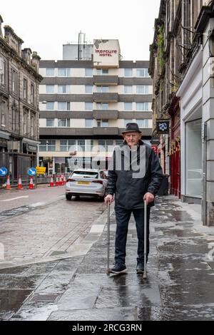 13. Juli 2023 Inverness, Highlands und Inseln, Schottland. Dies ist ein behinderter älterer Mann, der in Inverness mit Hilfe von zwei Gehstöcken läuft. Stockfoto