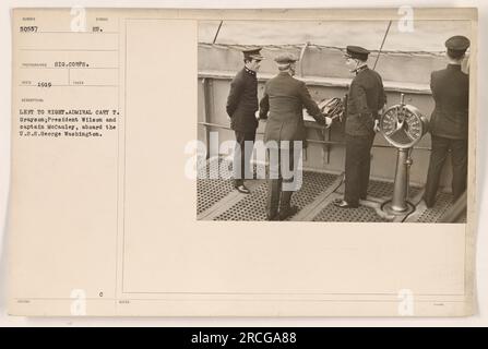 Admiral Cary T. Grayson, Präsident Wilson und Captain McCauley sind auf diesem Foto an Bord der U.S.S. zu sehen George Washington. Das Bild wurde 1919 von einem Fotografen des Signals Corps aufgenommen. Sie ist mit dem Symbol 50557 und einer Beschreibung mit der Aufschrift „Take 18BUED SYMBOL EU“ gekennzeichnet. Es wurden offenbar keine zusätzlichen Notizen oder fundierten Informationen bereitgestellt. Stockfoto