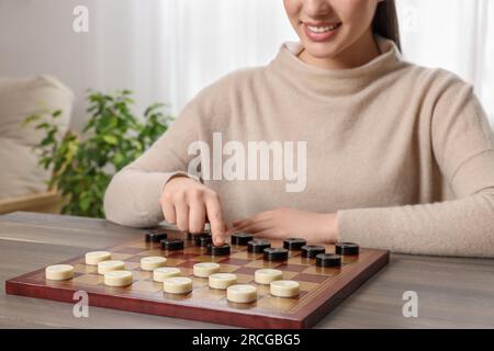 Dame spielen. Eine Frau, die über den nächsten Schritt am Tisch im Raum nachdenkt, die Schließung Stockfoto