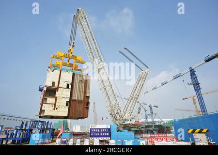 YANTAI, CHINA - 14. JULI 2023 - Ein großer Kran hebt das CA20-Modul in die Atominsel von Block 4 im Kernkraftwerk Shandong Haiyang in Y Stockfoto