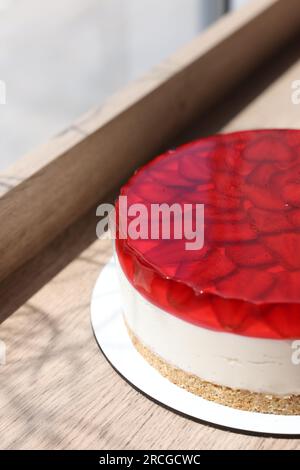 Köstlicher Käsekuchen mit Gelee und Erdbeeren auf einem Holztisch, Nahaufnahme Stockfoto