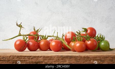 Ein Haufen Kirschtomaten auf einer hölzernen Oberfläche, Nahaufnahme der beliebten Tomatenvielfalt, die weltweit weit verbreitet ist, gegen strukturierte Tomaten Stockfoto