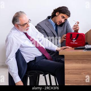 Die männlichen Mitarbeiter leiden von Herzinfarkt im Büro Stockfoto