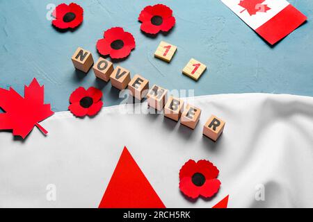 Mohnblumen mit kanadischer Flagge und Text 11. NOVEMBER auf blauem Hintergrund. Gedenktag Stockfoto