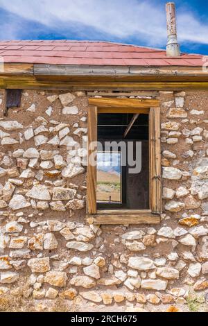 Das alte Felsenhaus in der Geisterstadt Rhyolite soll entweder ein Bergarbeiterhaus, ein Bordell oder ein Büro für die nahe gelegenen zwei Eisenbahnlinien sein. Stockfoto