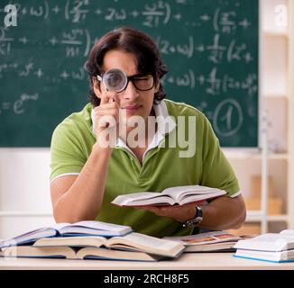 Der gutaussehende Schüler vor der Tafel mit Formeln Stockfoto