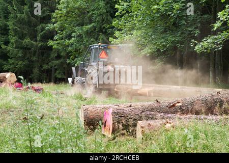 Rückansicht eines Traktors, der auf einem Holzeinschlagplatz arbeitet. Entwaldung durch Befall des Monokulturfichenwaldes durch Rindenkäfer. Juli 2023, Tschechien. Stockfoto