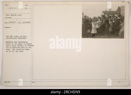 SGT. Musler, ein Fotograf des Signal Corps, hat dieses Bild am 19. November 1918 während des 1. Weltkriegs aufgenommen Das Foto zeigt Mitglieder der 9. Infanteriegruppe, 2. Division, die belgische Einheimische unterhalten. Germaine Van Valkenberg, Nichte des Bürgermeisters, kann gesehen werden, wie sie der Band einen großen Blumenstrauß und eine amerikanische Flagge spendet. Ihre Spende scheint spontan zu sein. Diese Beschreibung stammt aus den offiziellen Aufzeichnungen mit der Patientennummer 40005. Stockfoto