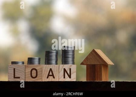 Wohnungsbaudarlehen, Reverse Mortgage und Ersparnisse für ein Immobilienkonzept : Hausmodell, Darlehensart und Münze auf Holzblöcken, Darstellung von Ersparnissen für ein Haus oder eine Fla Stockfoto