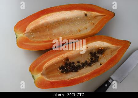 Reife und verzehrfertige Papayaschneiden. Lange Scheiben reifer Papaya mit weniger Samen im Inneren. Sie hat orangisch-gelbe Haut und ist weich zu berühren. S Stockfoto