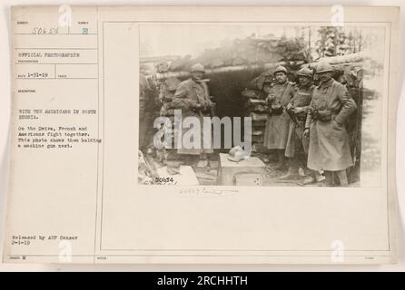 Amerikanische und französische Soldaten haben sich während des Ersten Weltkriegs auf dem Dwiva-Fluss in Nordrussland zusammengeschlossen Dieses Foto zeigt, wie sie zusammen ein Maschinengewehrnest besetzen. Das Foto wurde von einem offiziellen Kriegsfotografen aufgenommen, am 31. Januar 1919 empfangen und am 1. Februar 1919 vom Zensor der amerikanischen Expeditionstruppen veröffentlicht. Stockfoto
