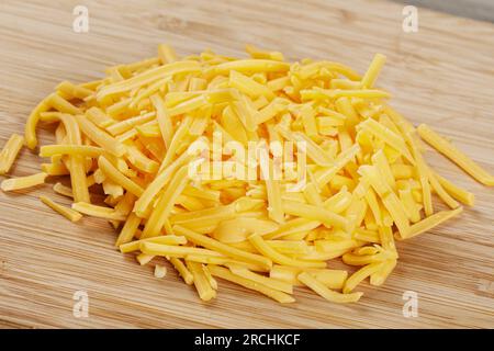 Nahaufnahme von köstlichem geriebenem Cheddar-Käse auf einem hölzernen Hintergrund mit Kopierbereich Stockfoto