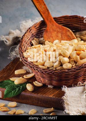 Geschälte Erdnüsse in einer Weidenschale. Das Stillleben des Dorfes. Werbefoto von Nüssen für Online-Shop oder Zeitschrift. Hintergrund. Stockfoto