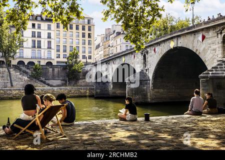 FRANKREICH. PARIS (75) 4TH. BEZIRK. PARIS PLAGES 2023. LEUTE, DIE AM QUAY DE SEINE AN DER PONT MARIE BRÜCKE SITZEN Stockfoto