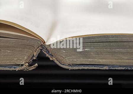 Ein offenes Buch. Ein antikes getragenes offenes Buch, das von oben gesehen wird, mit goldfarbenen Seitenkanten und einem Kopierbereich oben. Stockfoto