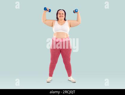 Fröhliche, dicke, übergewichtige junge Frau, die mit Kurzhanteln trainiert Stockfoto
