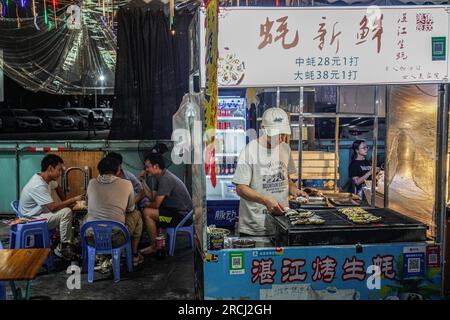 Guangzhou, China. 12. Juli 2023. Ein Mann kocht, während seine Gäste auf das Essen neben ihm auf einem Nachtmarkt warten. (Foto: Michael Ho Wai Lee/SOPA Images/Sipa USA) Guthaben: SIPA USA/Alamy Live News Stockfoto