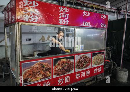 Guangzhou, China. 12. Juli 2023. Ein Mann kocht auf einem Nachtmarkt. (Foto: Michael Ho Wai Lee/SOPA Images/Sipa USA) Guthaben: SIPA USA/Alamy Live News Stockfoto