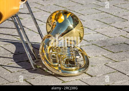 Die goldene Tuba liegt während einer Pause auf dem Boden, während eines Sommerfestivals Stockfoto