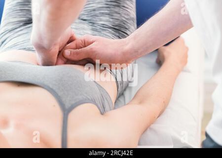 Therapeut führt eine Sitzung mit lokalisierter Massage in der Bauchregion, um die Gesundheit des Patienten in Bezug auf die inneren Organe zu verbessern. Stockfoto