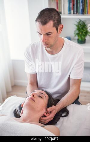 Therapeut, die eine lokale Massage im Schädelbereich unter Anwendung von kleinem, sanftem Druck durchführt. Die kraniosakrale Therapie. Stockfoto