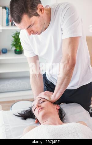 Therapeut, die eine lokale Massage im Schädelbereich unter Anwendung von kleinem, sanftem Druck durchführt. Die kraniosakrale Therapie. Stockfoto