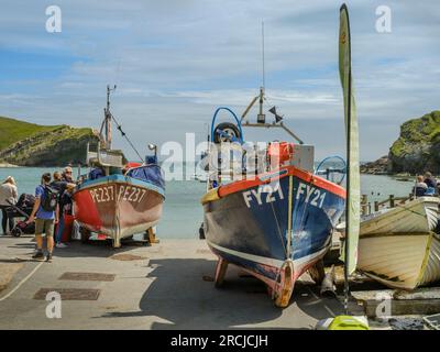 An einem Sommertag sind die kleinen Fischerboote, die an der Seilbahn am Lulworth Cove in Dorset liegen, bei den Touristen beliebt. Stockfoto