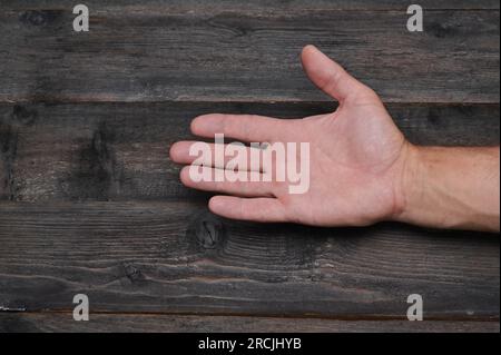 Nahaufnahme der Handfläche. Die Hand eines Mannes auf einem Hintergrund aus Holzbrettern. Stockfoto