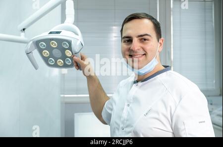 Professioneller männlicher Zahnarzt lächelnd am Arbeitsplatz in der Zahnarztpraxis in der Medizinischen Klinik. Stockfoto