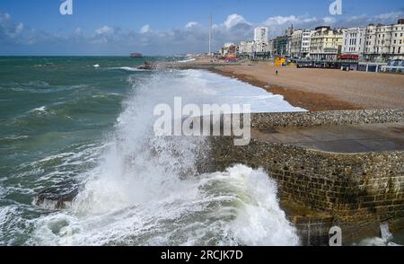 Brighton UK 15. Juli 2023 - Besucher werden nass, wenn sie sehen, wie riesige Wellen am Brighton Beach und am Ufer des Piers krachen, als ungewöhnlich starker Wind für Juli Batter Teile des Vereinigten Königreichs : Credit Simon Dack / Alamy Live News Stockfoto