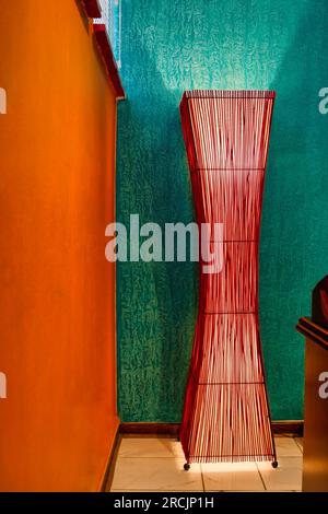 Eckeingang eines Designer-Heimbüros mit einer hohen Lampe aus Bambusstäbchen, die den Raum beleuchtet Stockfoto