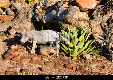 Gartendesign in afrika mit Tierskulpturen aus Holz, Nilpferden, Büffeln, Vögeln auf einem Felsbett und Aloe-Vera-Pflanzen Stockfoto