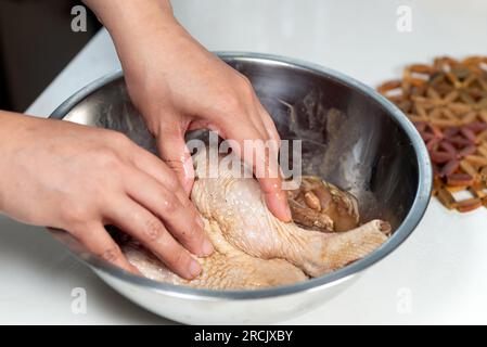 Marinieren Sie Hühnchen mit der Hand in einer Aluminiumschüssel Stockfoto