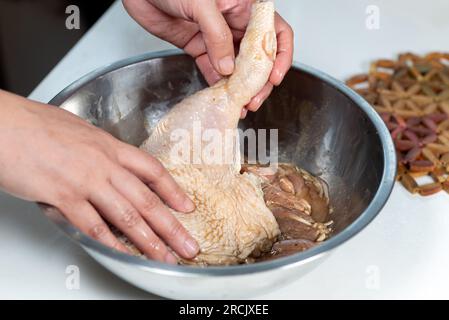 Marinieren Sie Hühnchen mit der Hand in einer Aluminiumschüssel Stockfoto