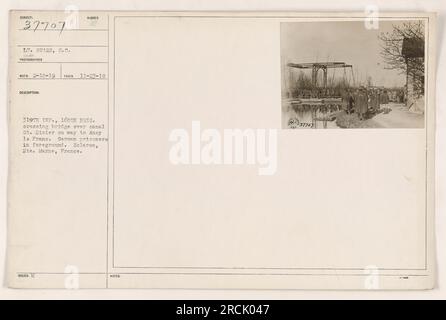 Amerikanische Soldaten der 319. Infanterie, 160. Brigade, angeführt von Lieutenant Sears, überqueren eine Brücke über Canal St. Disier auf dem Weg nach Ancy le Frane. Im Vordergrund sind deutsche Kriegsgefangene zu sehen. Das Foto wurde am 23. November 1918 in der Hei aufgenommen. Region Marne in Frankreich. Stockfoto