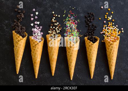 Eiscreme- oder Kuchendekoration mit Eiskrem-Zapfen auf schwarzer Oberfläche Stockfoto