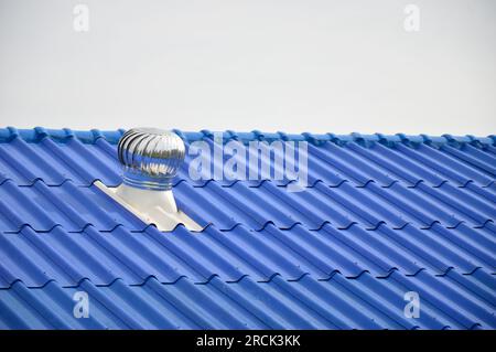 Das blaue Dach ist mit einer Windturbine zur Belüftung der Kühlluft auf dem Dach ausgestattet. Stockfoto