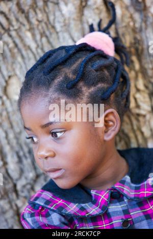 Porträt eines glücklichen kleinen afrikanischen Mädchens mit natürlichen Dreadlocks, das im Garten in ihrem Haus in der Gemeinde steht Stockfoto