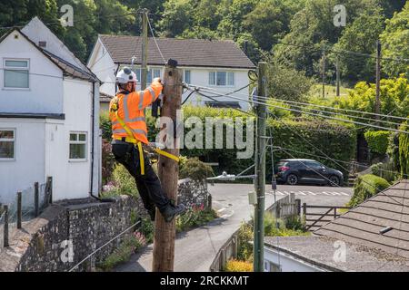 Ogi baut einen Telefonmast auf und installiert Glasfaserkabel für Breitbandverbindungen zum Wohnhaus in Wales, Großbritannien Stockfoto