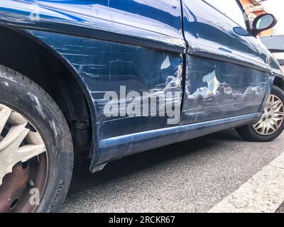 Blaues Auto, Delle in einer Tür auf der Straße nach einem kaputten Unfall. Verkratzte Karosserie. Verbeult. Stockfoto