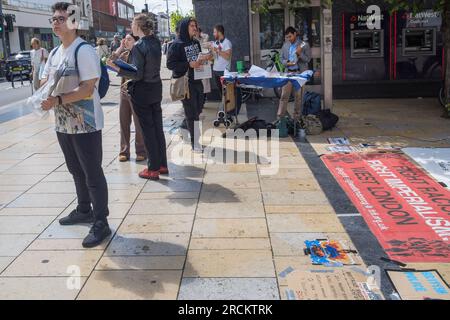 London, Großbritannien. 15. Juli 2023 Die Demonstranten in Hammersmith gegen das Gesetz über illegale Migration verteilen Flugblätter und sammeln Unterschriften, die besagen, dass es rassistisch ist, Sündenbock ist und Migranten und Asylbewerber kriminalisiert und ihnen ihre grundlegenden Menschenrechte vorenthalten. Die Regierung behauptet, sie sei mitfühlend, zeigt aber kein Mitgefühl und beabsichtigt, Migranten ungeachtet dessen einzusperren und nach Ruanda abzuschieben, ohne die Ursachen der Migration anzugehen. Peter Marshall/Alamy Live News Stockfoto