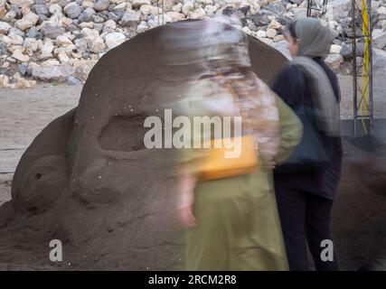 Zwei iranische Besucherinnen sehen eine Sandskulptur beim Babolsar National Sand Sculpture Festival, das am 13. Juli 2023 an der Südküste des Kaspischen Meeres in der Provinz Mazandaran, 235 km (146 Meilen) nördlich von Teheran, stattfindet. Die Stadt Babolsar in der Provinz Mazandaran im Norden des Iran veranstaltet ein Sandskulpturenfestival, das die Kreativität und das Talent lokaler Künstler zeigt. Dieses einzigartige Ereignis bietet die Gelegenheit, komplexe Sandskulpturen zu sehen, die von erfahrenen Künstlern geschaffen wurden, die nur Sand und Wasser nutzen, um das reiche kulturelle Erbe des Iran zu feiern und Stockfoto