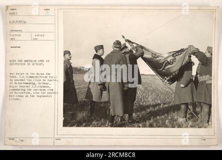 Generalmajor J.T. Diekman von der American Army of Occupation verleiht das Croix de Guerre an die 38. USA Infanterie in Neider-mendig, Deutschland. Die 38. Infanterie, Teil der 3. Division, wird für ihren Mut an der Marne geehrt. Auf dem Foto sieht man General Diekman, wie er das Kriegskreuz auf die Regimentalfarben kleben lässt. (Hinweis: Einige Teile der Beschreibung scheinen unvollständig oder abgeschnitten zu sein.) Stockfoto