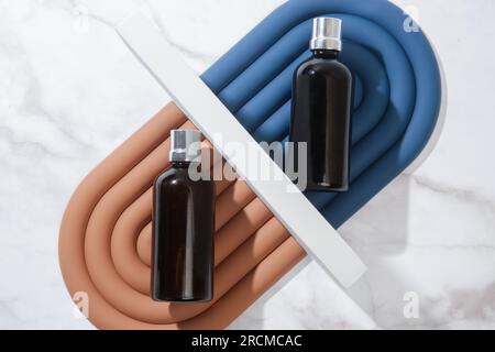 Kreative Studo-Aufnahme einer braunen Glaskosmetikflasche auf Marmorhintergrund Stockfoto